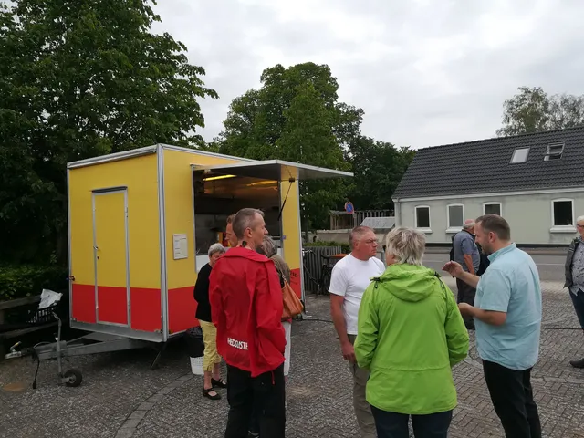 Gæster samles ved den gule pølsevogn til en privat fest